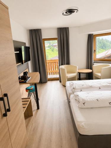 a hotel room with two beds and a desk at Gasthof Alpenblick in Tobadill