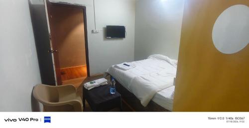 a small room with a bed and a suitcase at AB lodge in Coimbatore