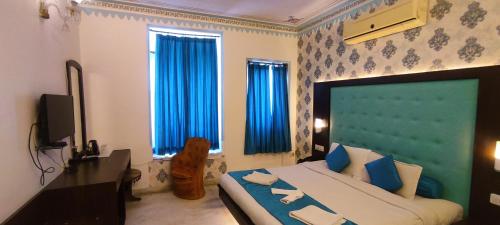 a bedroom with a large bed with blue curtains at Hotel Mandiram Palace in Udaipur