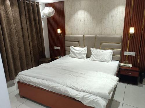 a bedroom with a large bed with white sheets and pillows at Hotel Deepjot in Karnal