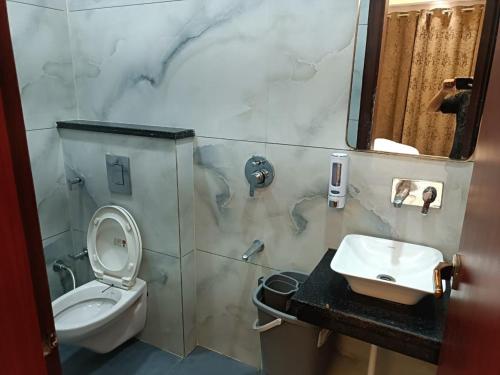 a bathroom with a toilet and a sink and a mirror at Hotel Deepjot in Karnal