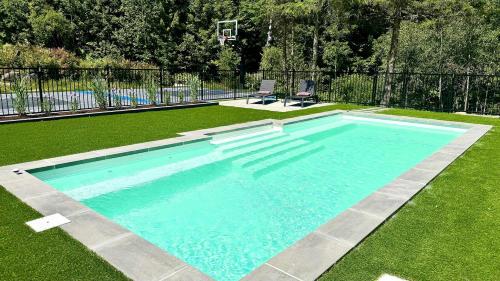 a swimming pool in the grass with two chairs at Howard Lodge & Spa in Saint Adolphe D'Howard