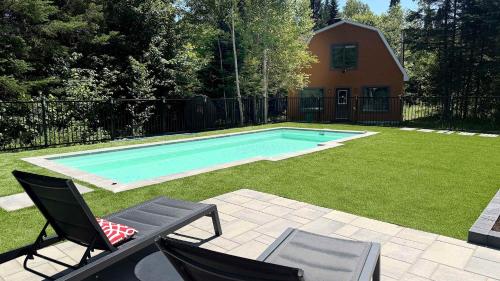 a swimming pool in a yard with two chairs at Howard Lodge & Spa in Saint Adolphe D'Howard