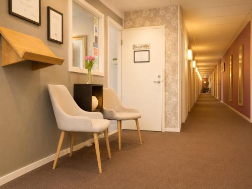 a hallway with two chairs and a table with flowers on it at Avenyn Hostel, former Le Mat in Gothenburg