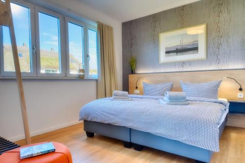 a bedroom with a blue and white bed with windows at Ferienwohnung Buntspecht 31 im Wreecher Idyll Rügen by ruyastay in Putbus