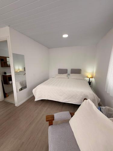 a white bedroom with a large bed and a couch at Apartamento El Arrayán in Tacuarembó