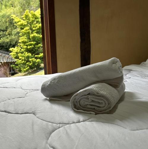a towel sitting on top of a bed with a window at Pousada Ritmos da Terra - Estadia de 6ª a Domingo in Angelina