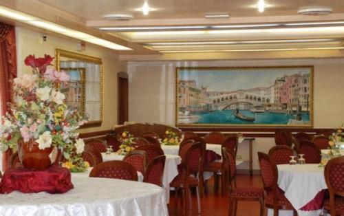 a dining room with tables and chairs with flowers on them at Hotel Burchiello in Mira