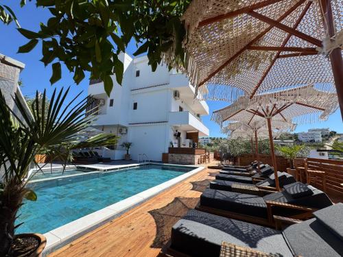 an outdoor pool with chairs and umbrellas next to a building at Vila Jeti in Ksamil
