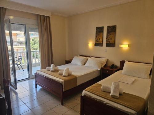 a hotel room with two beds and a balcony at Philippos Hotel in Paralia Katerinis