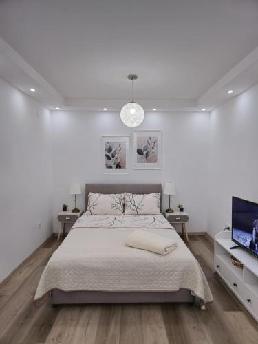 a white bedroom with a bed and a flat screen tv at Alfi apartments 1 in Belgrade