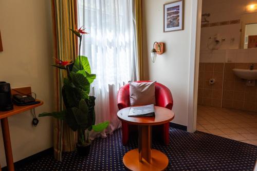 a room with a red chair and a table at Suite Hotel 900m zur Oper in Vienna