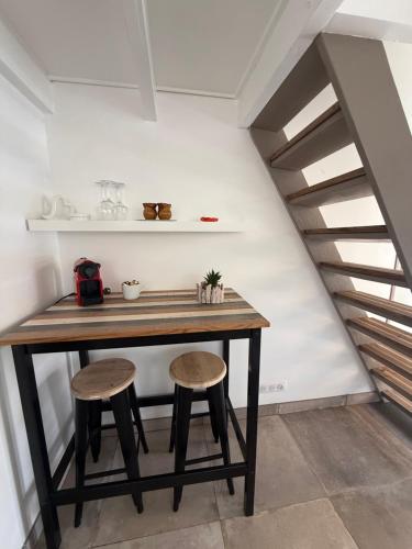 a table and two stools in a room with a staircase at Petit cocon avec mezzanine in Six-Fours-les-Plages