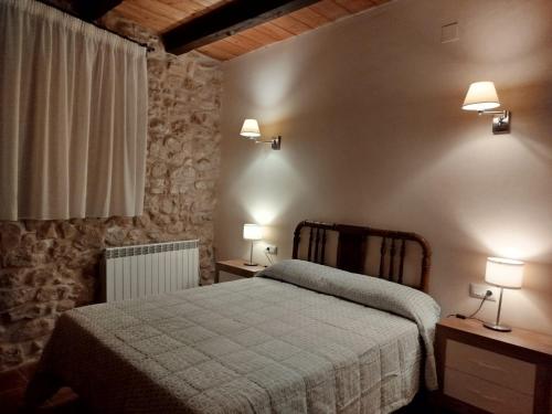 a bedroom with a bed and two lights on the wall at Casa Les Donfelises in Peñarroya de Tastavins