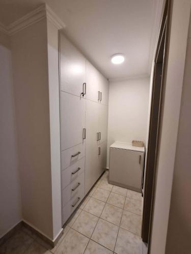 a laundry room with white cabinets and a refrigerator at Menelino, next to local bus and airport station in Argostoli