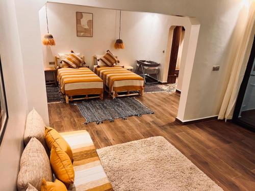 a living room with two beds and wooden floors at Villa TaouBa in Ghazoua