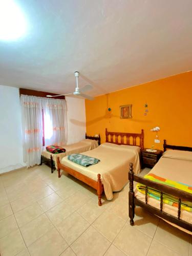 two beds in a room with yellow walls at Shekináh in Villa Cura Brochero