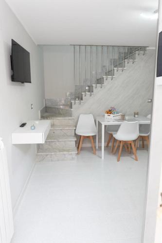 a white living room with a staircase with white chairs at A casa dello scalpellino in Contursi