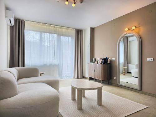 a living room with a couch and a table and a mirror at ODAYA Social Hotel Bansko in Bansko
