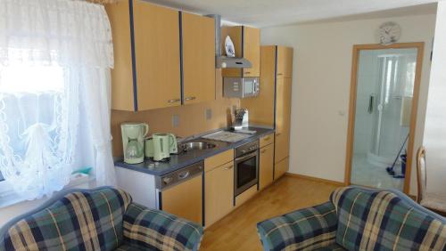 a kitchen with wooden cabinets and a sink and two chairs at Landidyll in Ummanz