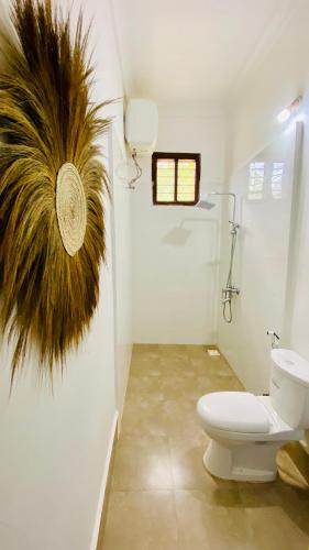 a bathroom with a toilet and a plant on the wall at Fish House in Nungwi
