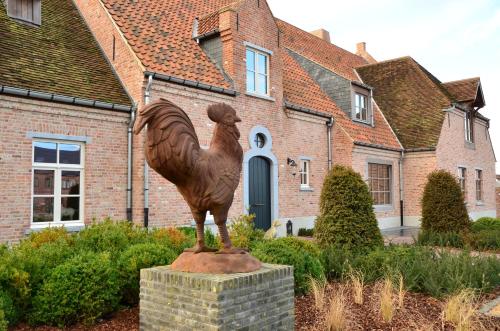 a statue of a chicken in front of a house at Boutique Hotel De Brakelhoen in Brakel