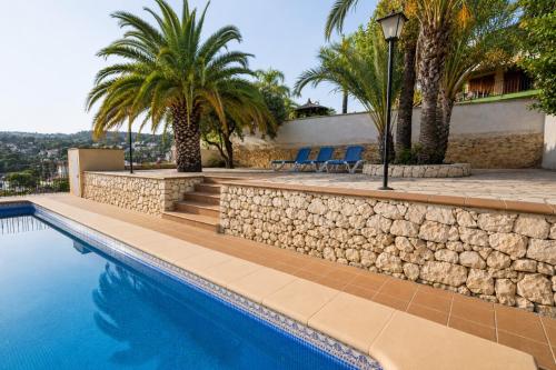 a swimming pool with palm trees and blue chairs at Villa Paula in Benissa