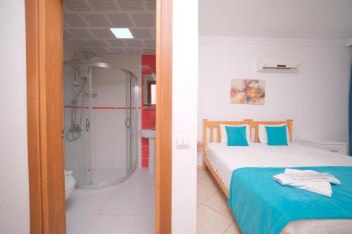 a bedroom with a shower and a bed with blue pillows at Kampüs Garden in Fethiye