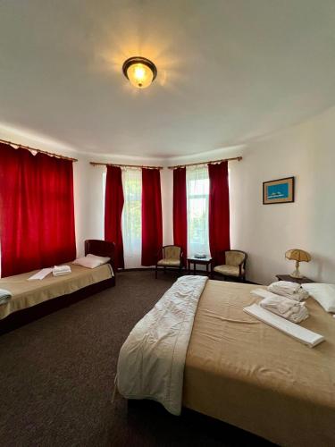 a hotel room with two beds and red curtains at Vila Randunica in Eforie Sud