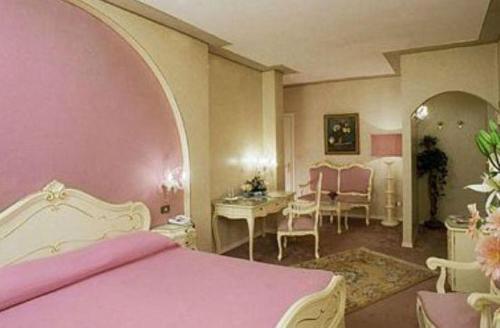 a bedroom with a pink bed and a table at Hotel Burchiello in Mira