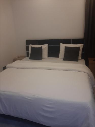 a large white bed with black pillows in a room at Jasper luxury homes in Abuja