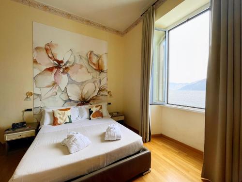 a bedroom with a large bed with a large window at Villa Belvedere Como Lake Relais in Argegno