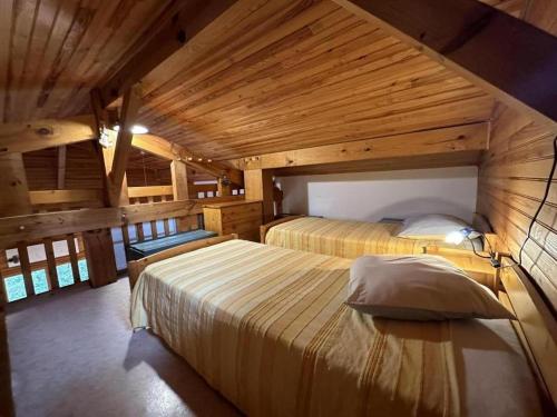 a bedroom with two beds in a room with wooden ceilings at Chalet des dunes in Biscarrosse