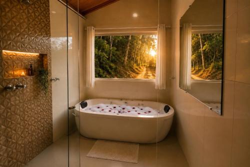 a bath tub in a bathroom with a window at Chalé Céu de Minas in Visconde De Maua