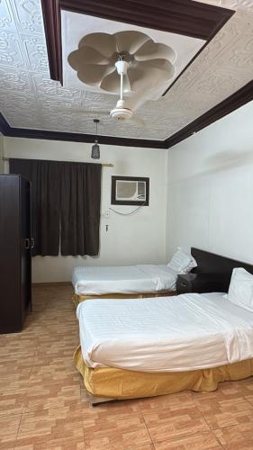 two beds in a room with a ceiling fan at الشامخة لشقق المخدومة 2 in Sharurah