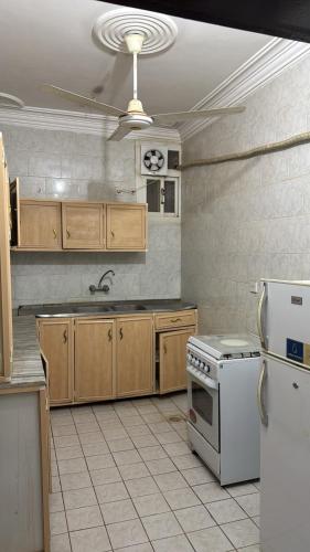 a kitchen with wooden cabinets and a white stove top oven at الشامخة لشقق المخدومة 2 in Sharurah
