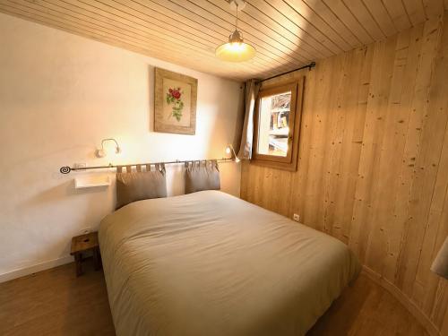 a bedroom with a white bed in a wooden wall at Le Génépi in La Plagne Tarentaise