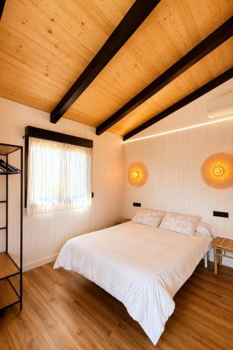 a bedroom with a large white bed and a wooden ceiling at Camping Preguntoiro in Sanxenxo
