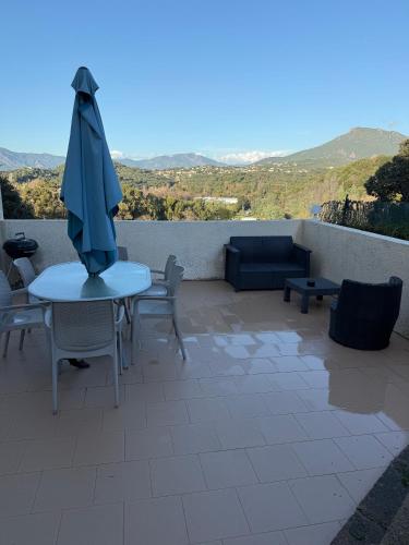 eine Terrasse mit Tisch, Sonnenschirm und Stühlen in der Unterkunft U refuggiu in Porticcio
