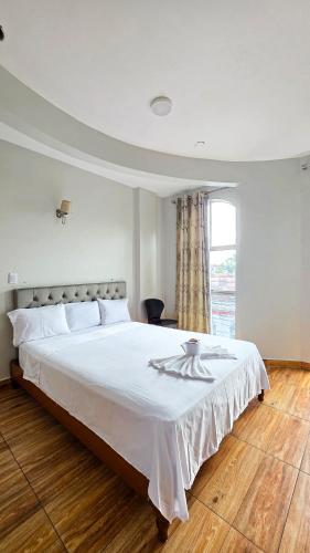 a bedroom with a large bed with white sheets and a window at Hotel Lirios Dorados in Iquitos