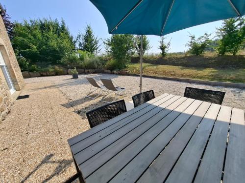 a wooden table with two chairs and an umbrella at Logis du fresne in Saint-Lormel