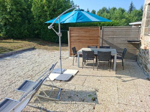 a patio with a table and a blue umbrella at Logis du fresne in Saint-Lormel