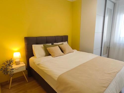 a bedroom with a large bed with a yellow wall at Olea relax apartman in Brčko