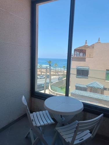 a table and chairs in a room with a view of the beach at Mehdia Beach Apartment in Kenitra