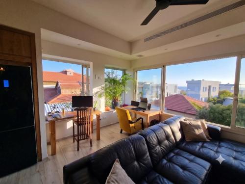 a living room with a couch and a desk and windows at Gador Sea View in H̱adera