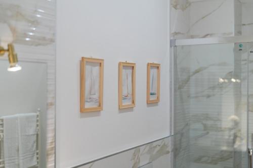 a group of three pictures on a wall in a bathroom at Santa Rosa Relais in Conca dei Marini