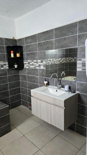 a bathroom with a sink and a mirror at Le Cocon de Tahiti Plage in Sada