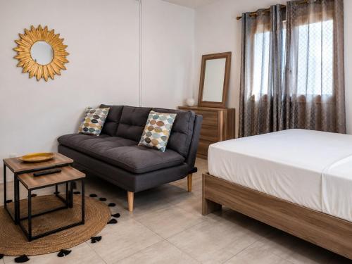 a bedroom with a bed and a couch and a mirror at Le Cocon de Tahiti Plage in Sada