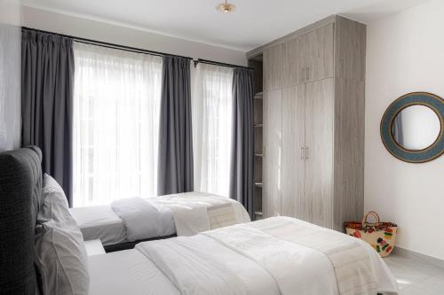 a bedroom with two beds and a mirror at Githima Cottage 10 at Swara Ranch in Nanyuki