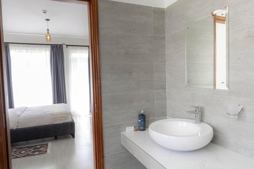 a white bathroom with a sink and a bed at Githima Cottage 10 at Swara Ranch in Nanyuki